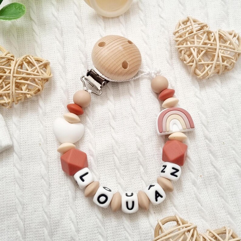 Attache tétine personnalisée arc en ciel pour bébé avec des perles silicone beige et terracotta, une perle motif coeur.