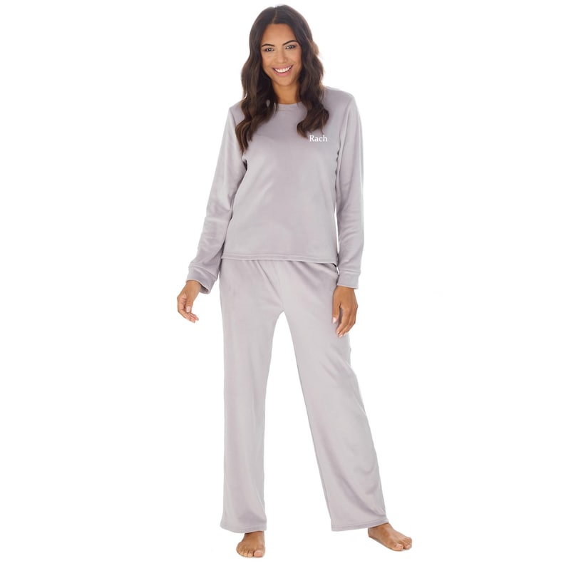 May include: A gray fleece pajama set with long sleeves and pants. The top has the word "Rach" embroidered on the front.