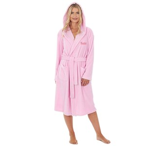 May include: A light pink hooded bathrobe with a matching belt and pockets. The word "Kate" is embroidered on the chest. The robe is made of a soft, plush material.