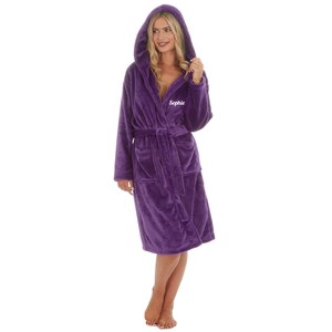 May include: A plush, hooded purple robe with a matching belt and pockets. The robe has the name "Sophie" embroidered on the chest. The robe is made of a soft, velvety material.
