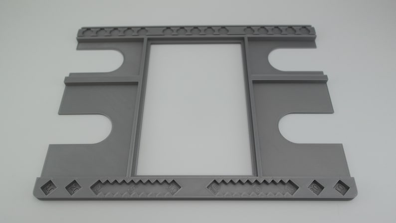 May include: A gray plastic frame with multiple slots for holding cards. The frame has a decorative border with a repeating pattern.