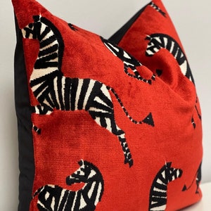 May include: Red velvet pillow with a black and white zebra print. The pillow has a black border.