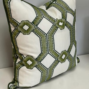 May include: A white pillow with a green geometric pattern. The pattern is made up of interlocking hexagons and diamonds.