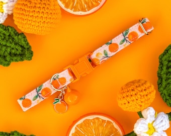Può includere: Collare per cani in crochet arancione e bianco con stampa di frutta arancione e un ciondolo. Il collare è su uno sfondo arancione brillante con frutta arancione all'uncinetto e un'arancia intera.