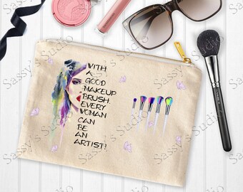May include: A beige canvas makeup bag with a zipper closure. The bag features a watercolor illustration of a woman's face with the text "With a good makeup brush, every woman can be an artist!" printed on the front. There are also several colorful makeup brushes and butterflies printed on the bag.