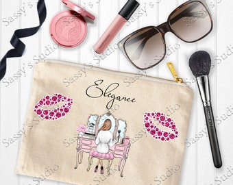 May include: A beige canvas makeup bag with a zipper closure. The bag features a pink and white illustration of a woman sitting at a vanity with a mirror. The words "Elegance" are printed on the bag. There are two pink glitter lips on the bag.