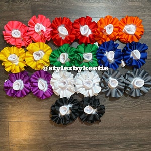 May include: A collection of 18 pairs of white ruffle socks with different colored ribbon trim. The colors include pink, red, green, blue, yellow, purple, white, gray, and black.