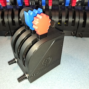 May include: A black 3D printed flight control panel with three knobs and two red and blue buttons. The panel is labeled "GRAVITYCON".