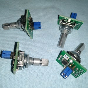 May include: Four green circuit boards with silver potentiometers and blue connectors. The boards have text on them, including "12000" and "12000".