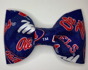 May include: A blue bow tie with a white and red pattern featuring the text "Ole Miss Rebels" repeated throughout.