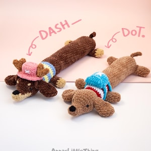 May include: Two crocheted dachshund toys made of brown yarn. The left toy, labeled DASH, wears a pink hat with antlers and a yellow and blue striped sweater. The right toy, labeled DoT, wears a blue and white backpack with red trim.