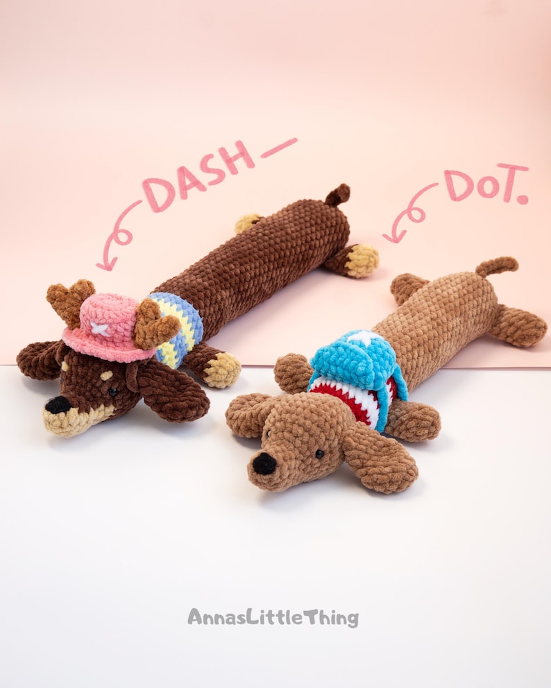 May include: Two crocheted dachshund toys made of brown yarn. The left toy, labeled DASH, wears a pink hat with antlers and a yellow and blue striped sweater. The right toy, labeled DoT, wears a blue and white backpack with red trim.