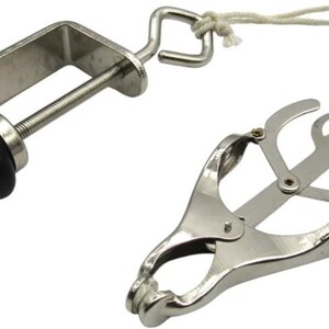 May include: A silver-colored clamp with a black knob and a hinged, scissor-like mechanism. A white cord connects the clamp to the scissor-like device. The device is designed to hold objects.