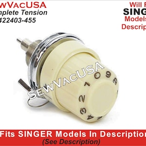 May include: A cream-colored sewing machine tension dial with a chrome-colored metal ring and a silver-colored metal pin. The dial has black numbers from 0 to 9. The text "SEWVACUSA Complete Tension 422403-455" is visible.