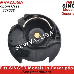 May include: Black plastic bobbin case for a Singer sewing machine. The case has a small yellow plastic piece inside. The text "SEWVACUSA" is printed on the case.
