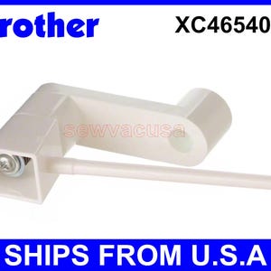 May include: White plastic sewing machine part with a lever and a small screw. The part is labeled with the model number XC4654051.