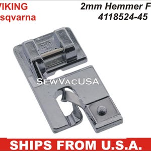 May include: A silver 2mm Hemmer Foot for Viking and Husqvarna sewing machines. The foot has a metal plate with the number 4118524-45 printed on it.