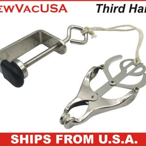May include: A silver-colored Third Hand tool with a clamp and adjustable jaws. The clamp has a black rubber grip. The tool is connected to a string. The text "Third Hand" is visible.