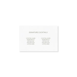 Op de afbeelding: Een witte kaart met de tekst "SIGNATURE COCKTAILS" bovenaan. Daaronder staan twee kolommen met de titels "COCKTAIL NAME, INGREDIENTS, DETAILS OR DESCRIPTION LISTED HERE". De kaart heeft een getextureerd oppervlak.