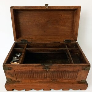 May include: A wooden box with a hinged lid and carved details. The box has a compartment with dividers inside and is made of dark brown wood.