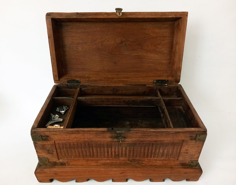 May include: A wooden box with a hinged lid and carved details. The box has a compartment with dividers inside and is made of dark brown wood.