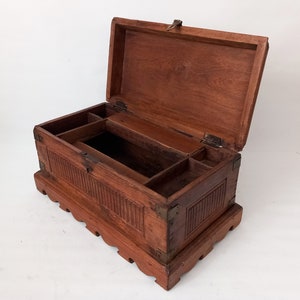 May include: A wooden box with a hinged lid and a carved design. The box has a brass latch and hinges. The box is open and the interior is divided into compartments.