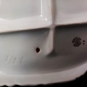May include: A white porcelain serving dish with four compartments and a scalloped edge. The dish has a stamp that reads "Porcelan Tajecar" and the number "67". The number "424" is also visible.