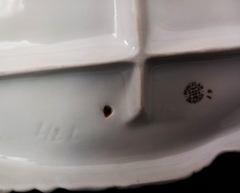May include: A white porcelain serving dish with four compartments and a scalloped edge. The dish has a stamp that reads "Porcelan Tajecar" and the number "67". The number "424" is also visible.