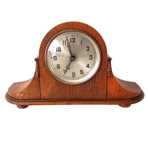 May include: A vintage wooden mantel clock with a white face and black hands. The clock has a Roman numeral clock face and is made of dark wood.