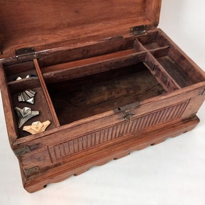May include: A wooden box with a hinged lid and carved details. The box is open and has a small compartment inside. There are several decorative pieces inside the box.