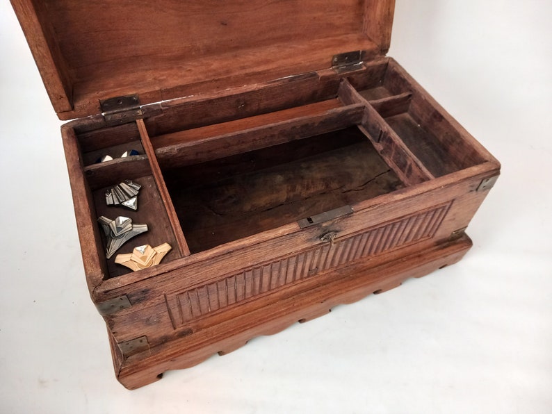 May include: A wooden box with a hinged lid and carved details. The box is open and has a small compartment inside. There are several decorative pieces inside the box.