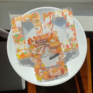 Puede incluir: Tres láminas de plástico transparente con pegatinas coloridas y brillantes que representan animales de dibujos animados, comida y diseños de temática navideña. Las pegatinas están dispuestas en un patrón festivo.