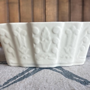 May include: A white ceramic mug with a black handle and the text "But First, Coffee" in a black, bold font. The mug is on a white surface.