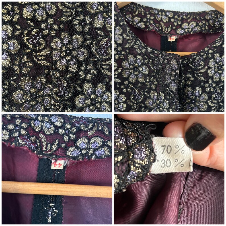 May include: A jacket featuring a black lace overlay with a metallic gold and purple floral pattern. The garment has a solid dark burgundy lining, a round neckline, and a tag displaying the number 44 along with a fabric composition label.