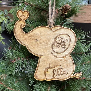 May include: Wooden elephant ornament with a heart on its trunk. It says "Ella" and "6 lbs 2 oz 6:50AM Thursday July 14th 2021".