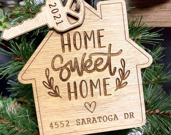 Puede incluir: Adorno de madera "Home sweet home" con un dije de llave. El adorno está decorado con un corazón y el texto "4552 Saratoga Dr."