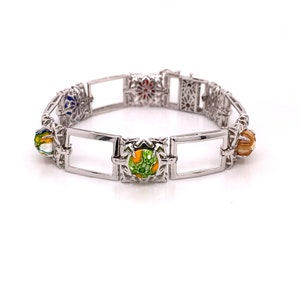 May include: A silver bracelet with colourful enamel accents. The bracelet features a series of square links with intricate designs and round enamel beads in shades of blue, red, green, yellow, and orange.
