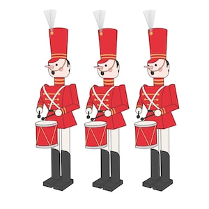 Puede incluir: Tres soldados de juguete tamborileros en fila. Cada soldado viste un uniforme rojo con detalles blancos, un sombrero alto rojo y botas negras. Sostienen baquetas y tocan tambores rojos con ribetes dorados. El fondo es blanco.