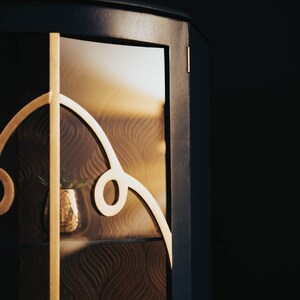 May include: A dark blue cabinet with a glass door and gold accents. The glass door has a decorative pattern and a small plant is visible inside.