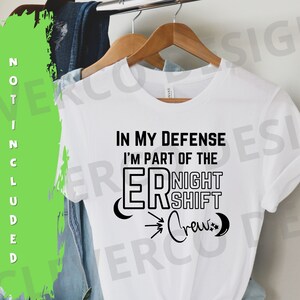 May include: White t-shirt with black text that reads "In my defence I'm part of the ER Night Shift Crew" with crescent moon graphics.
