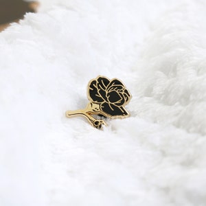 May include: Black enamel rose pin with gold-toned stem and leaves.