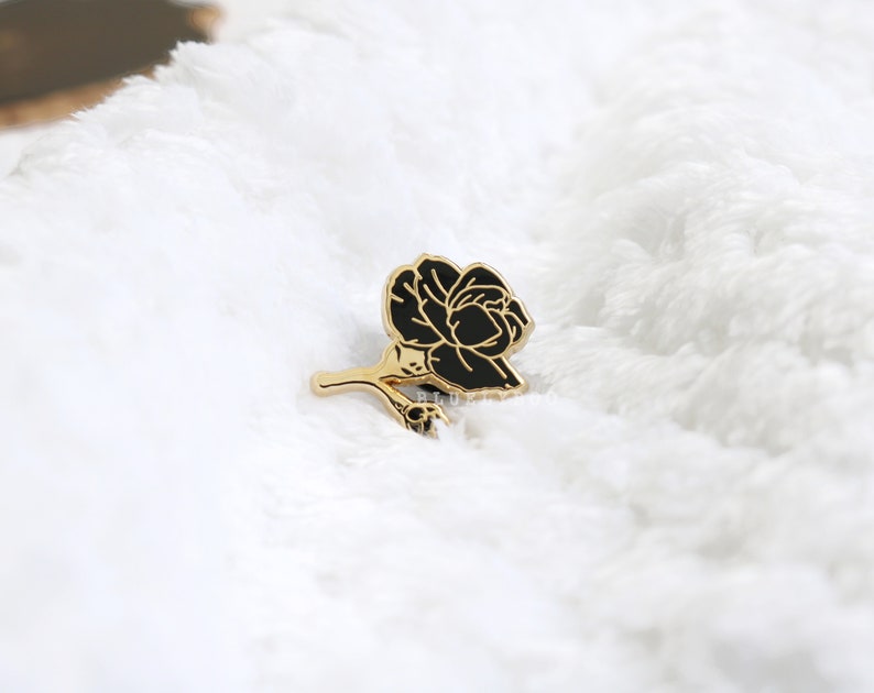 May include: Black enamel rose pin with gold-toned stem and leaves.