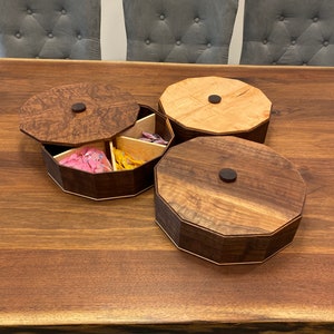 May include: Three wooden octagonal boxes with lids. The boxes are made of different types of wood, including walnut and maple. The boxes are arranged on a wooden table.