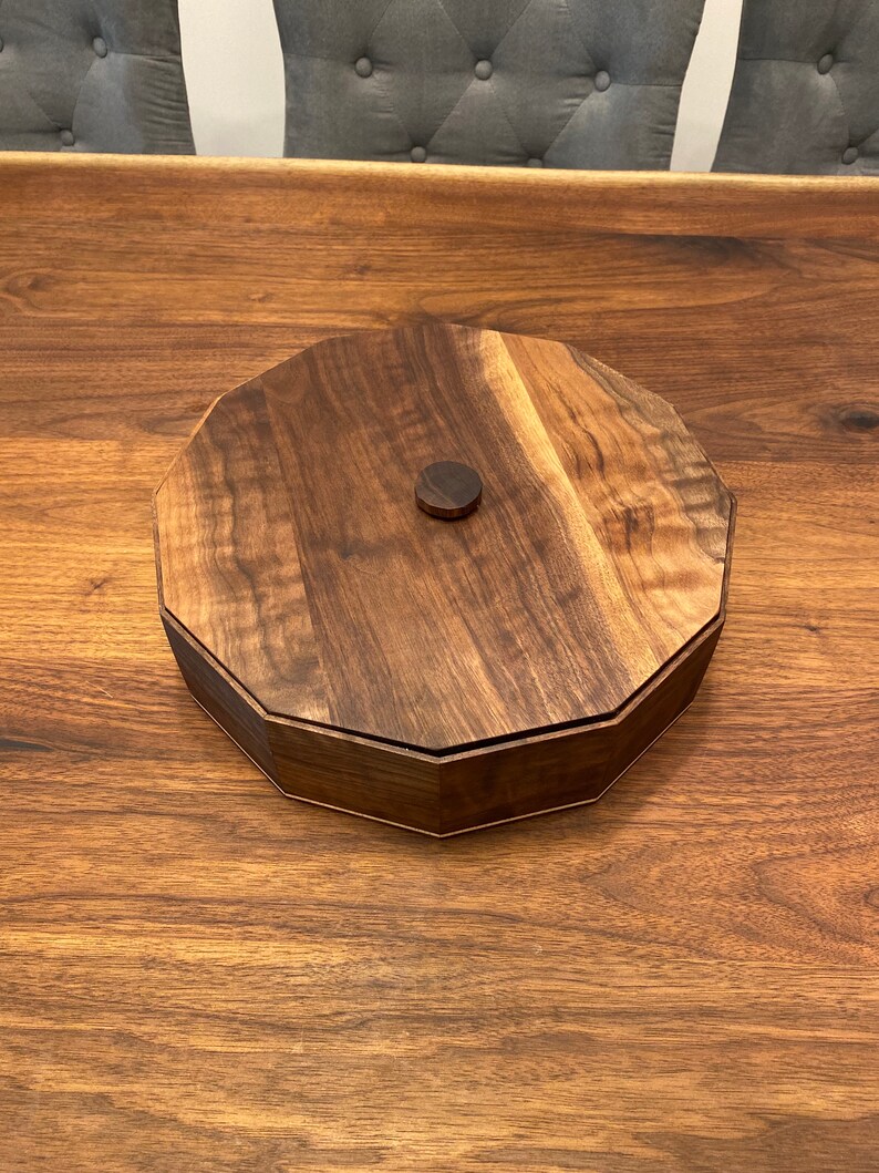 May include: A round wooden box with a lid, made of dark walnut wood. The lid has a small, round knob in the center.