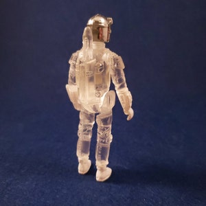K&ouml;nnte beinhalten: Eine durchsichtige Plastik-Actionfigur von Boba Fett aus Star Wars. Die Figur tr&auml;gt einen Helm und hat einen Jetpack auf dem R&uuml;cken.