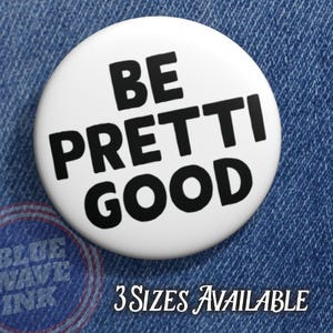 May include: A white button with the text "BE PRETTI GOOD" in bold black letters. The button is on a blue denim background. The text "3 SIZES AVAILABLE" is also visible.