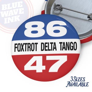 May include: A round button with a blue top section featuring the number 86 in white, a white middle section with the text "FOXTROT DELTA TANGO", and a red bottom section with the number 47 in white. The text "BLUE WAVE INK" is in the background.