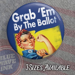 May include: A blue and yellow button with a woman's face and the text "Grab 'Em By The Ballot".