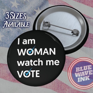 May include: Black and white button with the text "I am WOMAN watch me VOTE" with a blue checkmark over the "O" in WOMAN and the "O" in VOTE. The button is on a red, white, and blue American flag background.  The text "3 SIZES AVAILABLE" is in the upper left corner of the image.  A smaller blue, white, and red circle with the text "BLUE WAVE INK" is in the lower right corner of the image.