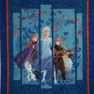 May include: A quilted wall hanging featuring characters from the animated film Frozen. The design includes Elsa, Anna, Kristoff, Olaf, and Sven, set against a blue and teal background with floral and leaf accents. The quilt has a blue border with an orange inner border.